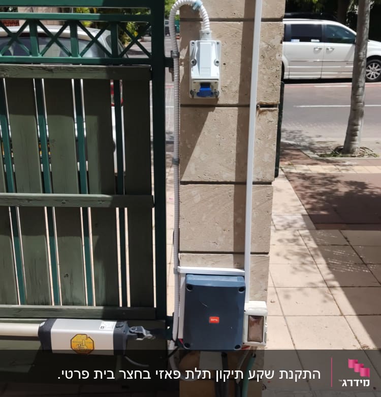 תיבת חשמל מותקנת על עמוד אבן ליד שער